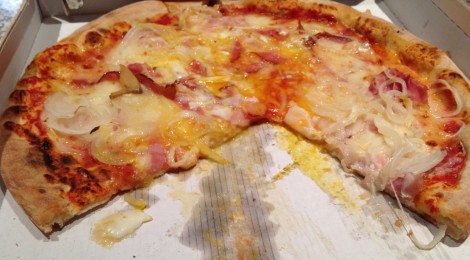 A pizza with egg cracked on the top a soon as it leaves the oven.